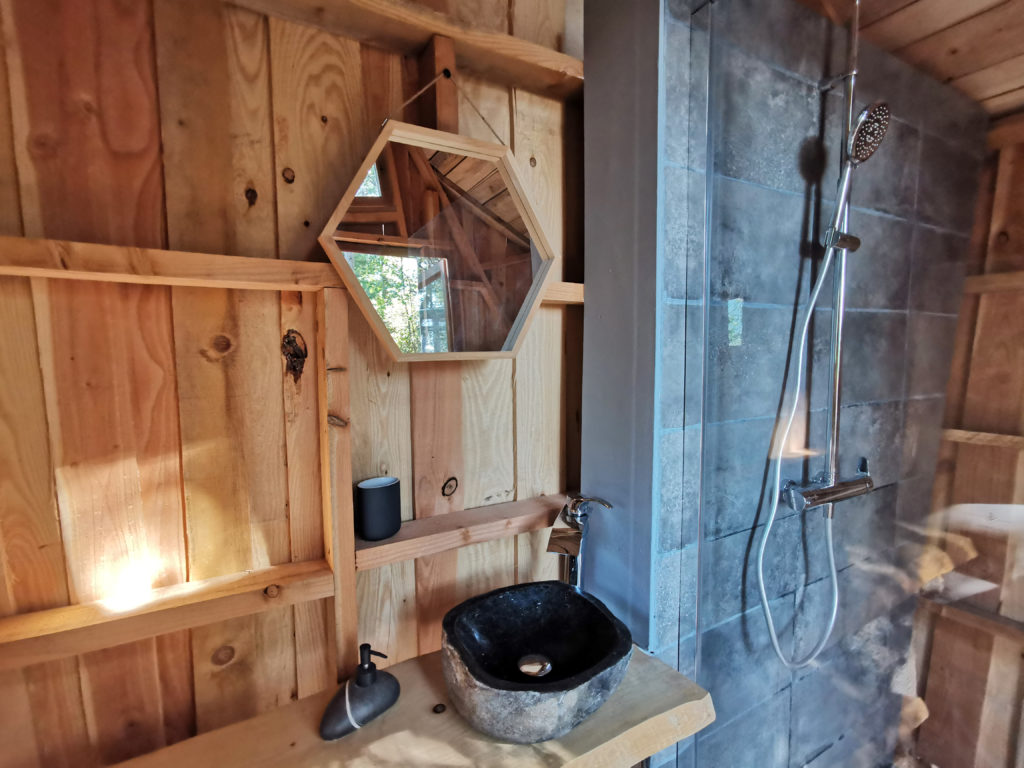 Salle de bain bulle transparente Olea avec douche et lavabo dans cabane en bois
